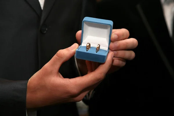 Bruidegom houdt een doos met goud trouwringen close-up — Stockfoto