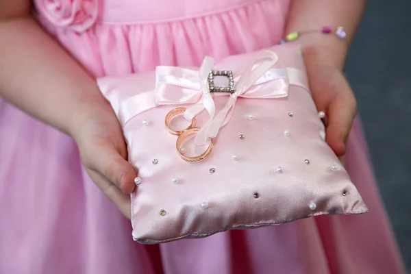 Dama de honor sostiene un cojín decorativo con anillos de oro de boda — Foto de Stock