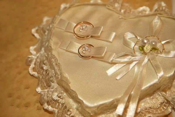 Zlaté snubní prsteny leží na dekorativní polštář — Stock fotografie