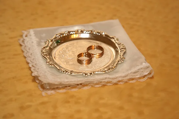 Gold wedding rings lie on a metal plate — Stock Photo, Image