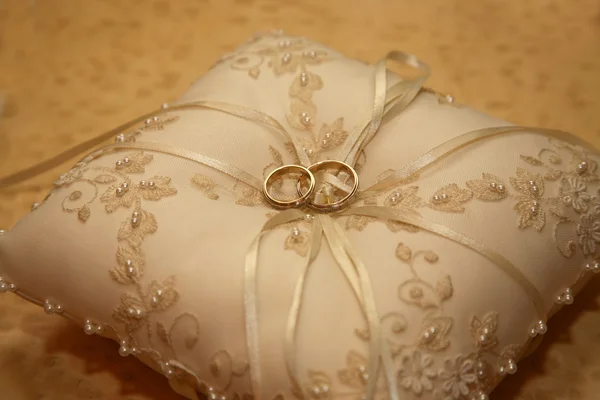 Anillos de boda de oro se encuentran en una almohada decorativa — Foto de Stock