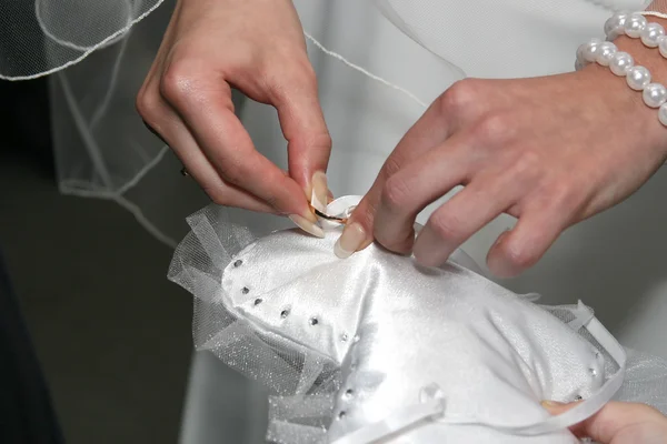 Невеста снимает обручальное кольцо с декоративными подушками — стоковое фото