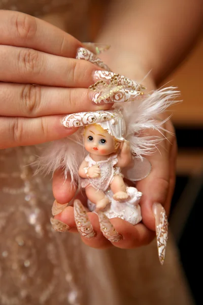 Bruden med manikyr hålla en leksak docka — Stockfoto