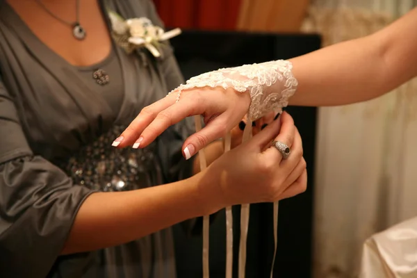 Подружка невесты помогает невесте носить повязку на руке — стоковое фото