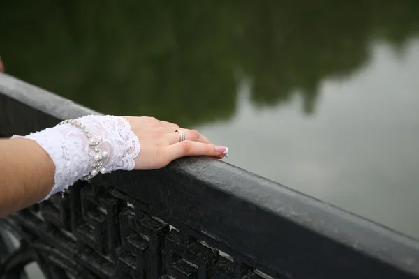 bride\'s hand rests on the railing of the bridge