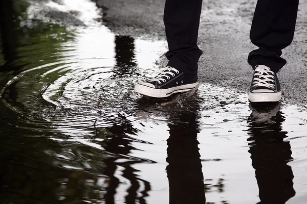 man stops with his foot in a puddle