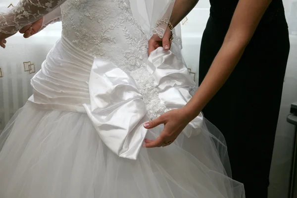 Demoiselle d'honneur aide à corriger l'arc sur la robe de la mariée — Photo