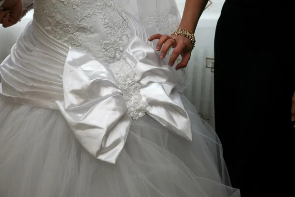 Подружка невесты помогает исправить лук на платье невесты — стоковое фото