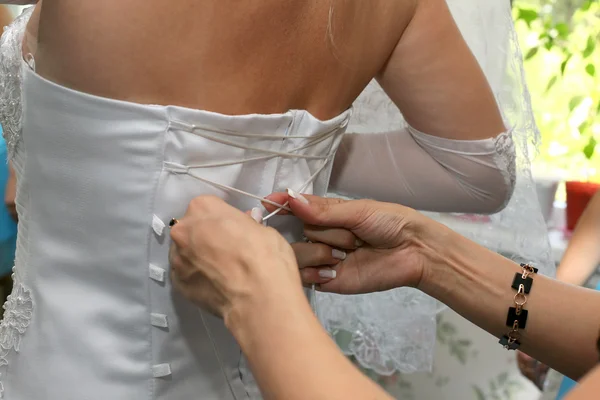 Η νονά βοηθάει να φορέσει το φόρεμα της νύφης από το πίσω μέρος — Φωτογραφία Αρχείου