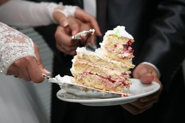Gelin ve damadın ellerinde düğün pastasından bir parça kes.