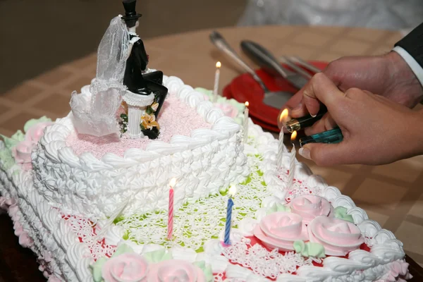 Noiva e noivo acender as velas em um bolo de casamento — Fotografia de Stock