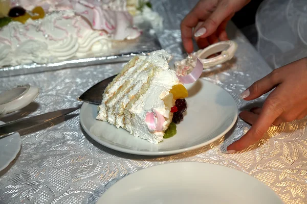 Cortar un pedazo de pastel de boda en el plato junto a la novia —  Fotos de Stock