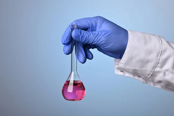 Врач держит розовую жидкость в химической фляжке — стоковое фото