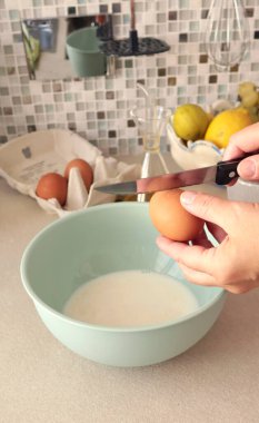 İsimsiz biri hamuru kaseye koyar ve bir yumurtayı bıçakla kırar. Organik, glütensiz malzemelerle sağlıklı beslenme. Ev yemeği. Yüksek kalite fotoğraf