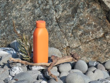 Plastic orange beauty bottle against backdrop of natural elements. Cosmetics and facial and hair care. Mock-up template for design. Eco-friendly products. Background, design composition. High quality