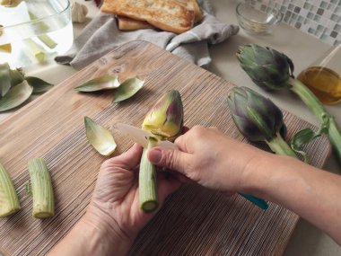 İsimsiz biri evde enginar soyuyormuş. Sağlıklı beslenme ve geleneksel İtalyan yemeği. Taze mevsimlik tarım ürünleri. Yüksek kalite fotoğraf