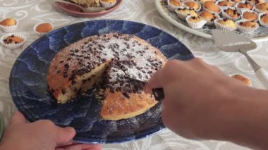 İsimsiz biri seramik tabağa çikolatalı pasta dilimi koymuş. Tatiller ve yaşam tarzı. Masa örtüsüyle kaplı yemek. Yüksek kalite 4k görüntü