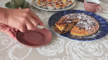 İsimsiz biri çikolatalı pastayı tabağa koyar. Tatiller ve yaşam tarzı. Masa örtüsüyle kaplı yemek. Yüksek kalite 4k görüntü