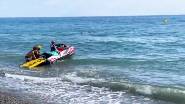 Yazın çocuğun tekneye binmesine yardım eden bir adam. Denizdeki cazibe ve eğlence. Spor ve eğlence sektörü. Yüksek kalite 4k görüntü