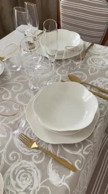 Klasik beyaz sofra takımı, gözlük ve altın jantlı kadehlerle Noel sofrası. İtalyan seramik sofra takımı. Estetik ve yaşam tarzı. İç dizayn. Yüksek kalite 4k görüntü