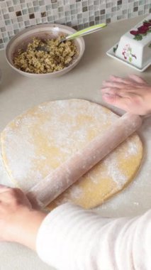 Kadın Avrupa 'da mutfak tezgahında merdaneyle hamuru yuvarlıyor. Antika yemekler ve mozaik fayanslar çalışma alanını dekore eder. Sağlıklı beslenme. Yüksek kalite 4k görüntü