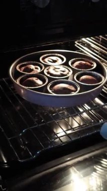 İsimsiz biri fırından folyo kaplı bardaklarda fırından fırınlanmış kek ve çikolatalı şekerleme çıkarıyor. Hobiler ve evde tatlı yapmak. Yüksek kalite 4k görüntü