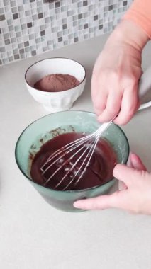 İsimsiz biri kaseden erimiş çikolata döker ve malzemeleri karıştırır. Evde tatlı yapıyorum. Hobiler ve yaşam tarzı. Yüksek kalite 4k görüntü