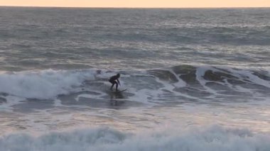 Gün batımında sıcak dalış kıyafeti içinde sörf yapan biri. İtalya 'da kış sporları. Sağlık, deniz ve doğa. Yüksek kalite 4k görüntü