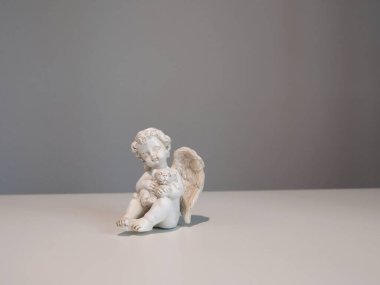 Beyaz arka planda tasarım için hayvan köpeği olan beyaz seramik melek heykelciği. İnanç, semboller ve gelenekler. Yüksek kalite fotoğraf