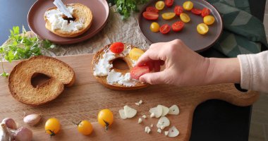 İsimsiz biri mutfakta kremalı keçi peyniri ve vişneli domatesli bruschetta hazırlıyor. İtalyan mutfağı, yüksek kaliteli tarım malzemeleri. Yüksek kalite fotoğraf