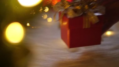 El kadını Noel zamanı kırmızı hediye kutusunu beyaz yüne bokeh ışıkları ile koyuyor..
