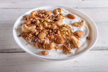 Yunan yoğurdu, granola, badem, ceviz, beyaz ahşap arka planda ceviz. Kapat..