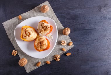 Siyah ahşap arka planda kaymak, fındık ve süt kremalı hurma tatlısı. Üst görünüm, boşluk kopyala.