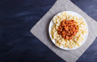 Siyah ahşap arka planda kıymalı Farfalle bolonez makarnası. Üst görünüm, boşluk kopyala.