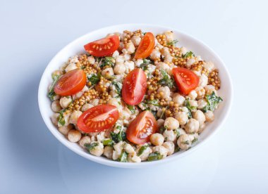 Haşlanmış nohut salatası, peynir, roka, hardal ve vişne domatesleri beyaz arka planda izole edilmiş, yakın plan..