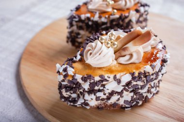 Çikolata parçalı kekler ve beyaz arka planda tahta tahtada krema süslemeleri. seçici odaklanma, kapat.