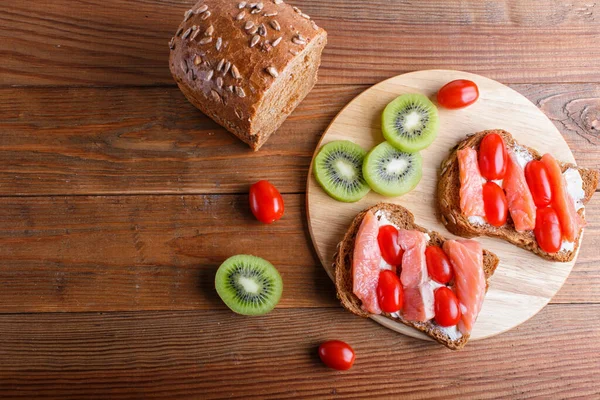 Smoked salmon sandwiches with butter on wooden background. cherry tomatoes. top view, copy space.