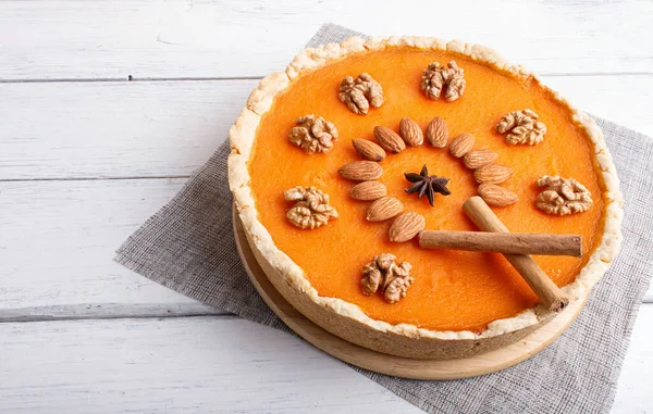 Traditional american sweet pumpkin pie decorated with nuts, on white wooden background. close up.