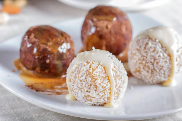 Enerji topları çikolatalı karamelli kekler ve hindistan cevizi beyaz tabakta keten peçetede, seçici odak, kapat.