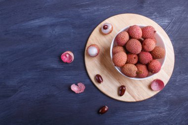 lychee in a white plate on a black wooden background, top view, flat lay, copy space. clipart