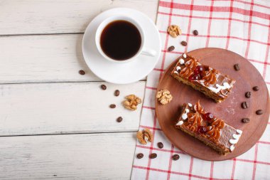 Tahta mutfak tahtasına karamel kremalı bir parça pasta ve bir fincan kahve, beyaz arka plan, üst manzara, düz yatak, kopyalama alanı..