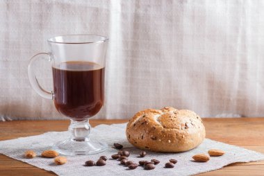 Ahşap arka planda çörek ve keten tekstil kaplı bir bardak kahve. Kapat, boşluğu kopyala.