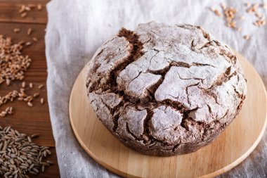 Çavdar ekmekli mayasız ev yapımı ekmek ve rustik ahşap arka planda buğday taneleri. Kapat..