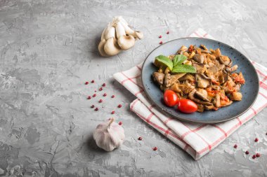 Gri beton arka planda domatesli kızarmış istiridye mantarı. Yan görünüm, boşluk kopyala.