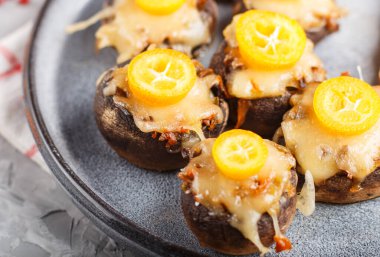 Gri beton arka planda peynirli, kumkatlı ve bezelyeli kızarmış şampiyonlar. seramik plaka, kenar görünüm, yakın çekim, seçici odak.