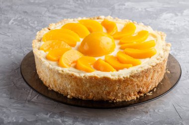 Gri beton arka planda yuvarlak şeftalili cheesecake. Yan görünüm, kapat.