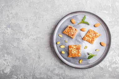 Gri beton arka planda gri seramik tabakta geleneksel Arap tatlıları. Üst görünüm, boşluk kopyala.