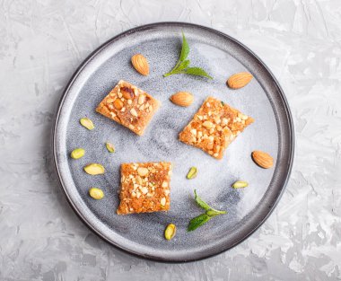 Gri beton arka planda gri seramik tabakta geleneksel Arap tatlıları. Üst görünüm, kapat.