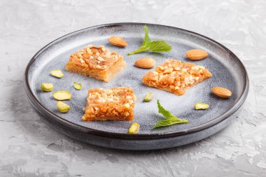 Gri beton arka planda gri seramik tabakta geleneksel Arap tatlıları. Yan görünüm, kapat.