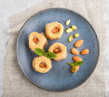 Kunafa, gri beton arka planda mavi seramik tabakta geleneksel Arap tatlıları. Üst görünüm, kapat.